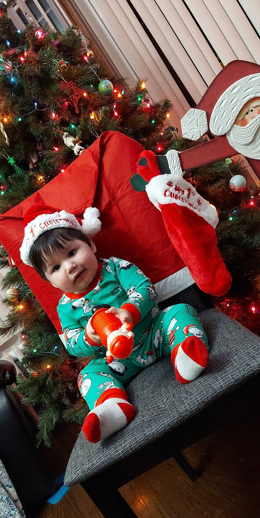 Erik is registered to the contest to win money with this photo: baby_toddler_clothing, christmas, christmas_decoration, christmas_eve, christmas_ornament, christmas_tree, event, fun, green, happy, holiday, holiday_ornament, human_body, lap, ornament, person, red, smile, snapshot, toddler