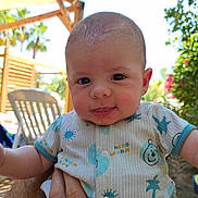 Nino a rejoint le concours — aidez-le/la à gagner de superbes lots ! baby, infant, child, person, outdoor, sunlight, greenery, clothing, onesie, hand, holding, face, smile, expression, nature, garden, chair, wood, daylight, cute
