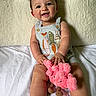 baby, child, smiling, plush_toy, pink, sitting, indoors, cute, happy, face, clothing, shorts, striped, skin, person, young_child, texture, background, soft, toy