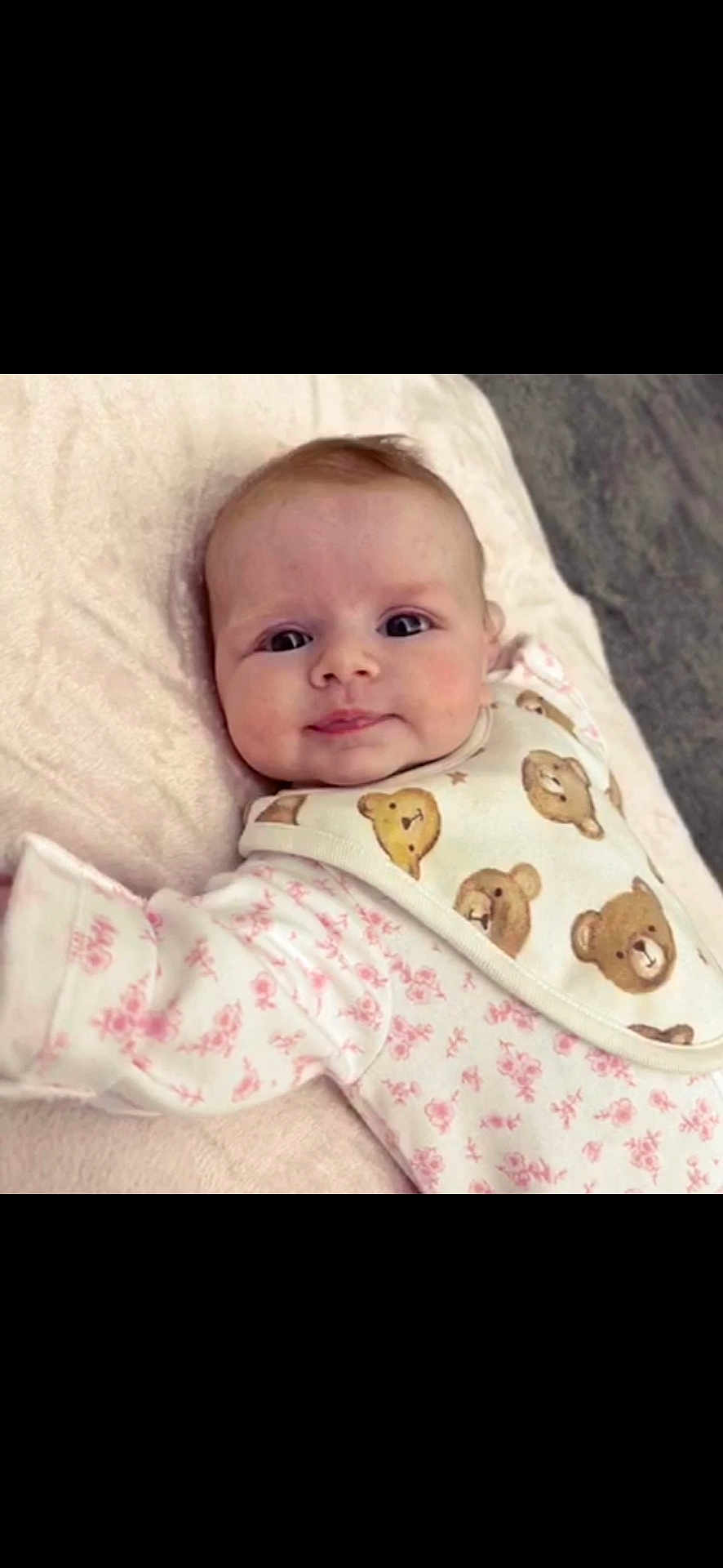 Madison joined the competition — help win amazing prizes! baby, infant, face, smile, blanket, bib, teddy_bear, floral_pattern, clothing, cute, child, soft, lying_down, pink, white, young, portrait, indoors, person, happy