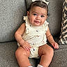baby, child, infant, couch, sofa, smile, face, hair_bow, socks, clothing, portrait, cute, indoors, person, seated, happy, skin, furniture, babygirl, closeup