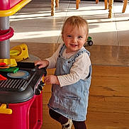 Anna a rejoint le concours — aidez-le/la à gagner de superbes lots ! child, toddler, toy_kitchen, denim_pinafore, sippy_cup, hardwood_floor, sunlight, smile, playing, indoor, wooden_chair, dining_table, toy_car, shoes, tights, happy, face, portrait, kitchen_toy, furniture