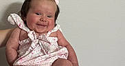 Riley is registered to the contest to win money with this photo: baby, infant, child, smile, pink_bow, romper, cute, happy, person, skin, face, arm, hand, foot, toes, indoor, wall, holding, portrait, head
