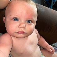 Aspen is registered to the contest to win money with this photo: baby, child, blue_eyes, diaper, skin, face, arm, shoulder, chubby_cheeks, indoor, leather, couch, curious_expression, close_up, portrait, human, infant, sitting, looking_at_camera, cute