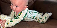 Aspen is registered to the contest to win money with this photo: baby, child, crawling, pajamas, cactus_pattern, couch, brown, indoor, face, hands, feet, clothing, infant, young_child, curious, soft_light, rosy_cheeks, blue_eyes, expression, home