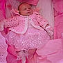 baby, sleeping, pink_clothing, crocheted_sweater, lace_dress, soft_blankets, cushions, newborn, infant, cozy, indoor, cute, child, warm, resting, glitter, decorative, peaceful, portrait, small