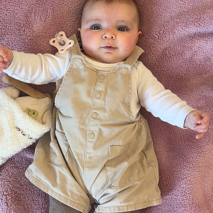 Jeanne a rejoint le concours — aidez-le/la à gagner de superbes lots ! baby, infant, blanket, pink, overalls, tights, pacifier, plush_toy, soft_texture, lying_down, clothing, cute, child, indoor, portrait, looking_at_camera, human, small_child, relaxed, comfort