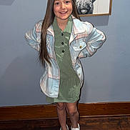 Harlee is registered to the contest to win money with this photo: child, girl, smile, standing, long_hair, green_dress, plaid_jacket, white_shoes, wood_floor, blue_wall, framed_art, light_switch, indoor, casual_clothing, portrait, happy, hands_on_hips, home, fashion, young