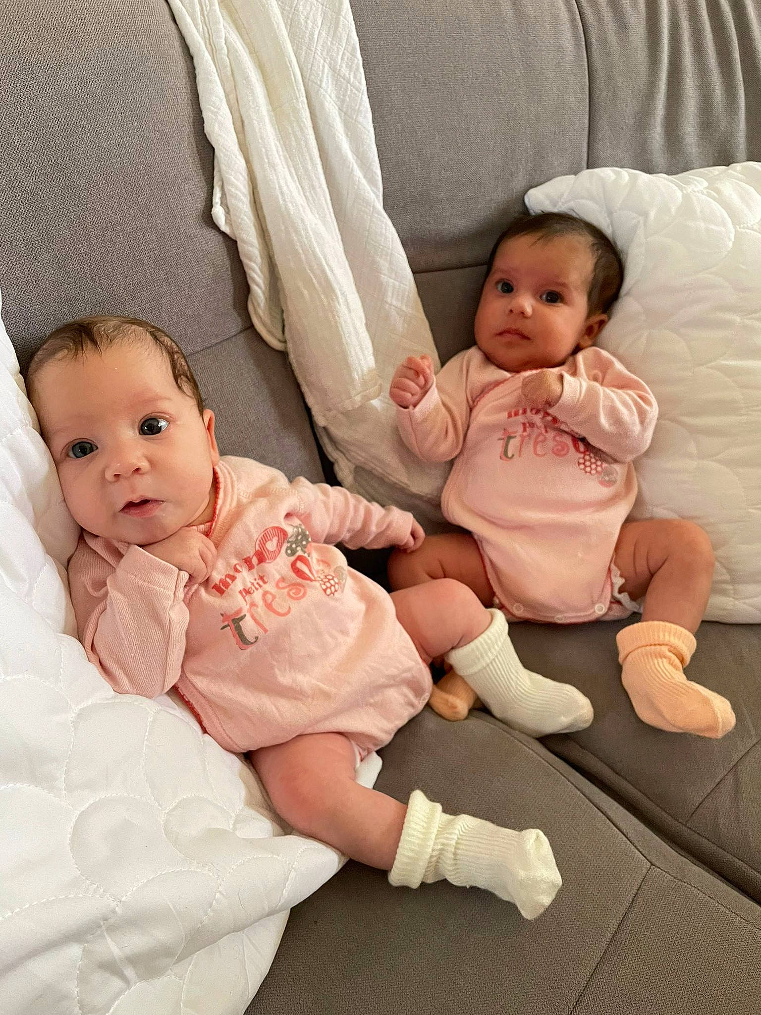 Alya participe au concours pour gagner de l'argent avec cette photo : arm, baby, baby_toddler_clothing, cheek, comfort, eye, face, finger, gesture, hairstyle, hand, human_body, lap, linens, neck, person, pink, skin, sleeve, sock