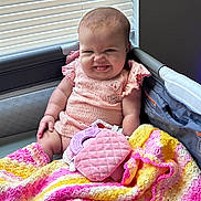 Rubyann is registered to the contest to win money with this photo: baby, infant, child, smiling, sitting, portrait, playpen, blanket, crochet, colorful, pink, yellow, toy, plush_toy, indoor, window, blinds, clothing, happy, cozy