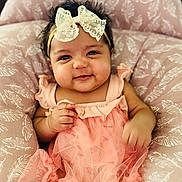 Amara joined the competition — help win amazing prizes! baby, infant, child, smile, face, headband, bow, dress, pink, peach, cushion, pattern, soft, comfortable, cute, happy, portrait, indoors, person, baby_girl