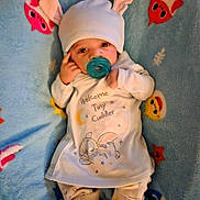 Daymeir is registered to the contest to win money with this photo: baby, infant, pacifier, hat_with_bunny_ears, blanket, blue_blanket, onesie, baby_clothes, newborn, lying_down, cute, booties, socks, cartoon_print, bunny, portrait, indoors, small_person, headwear, sleepy