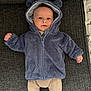 baby, child, infant, blue_jacket, hood, ears, couch, fabric, texture, person, clothing, cute, smile, face, eyes, indoor, laying_down, warm_clothing, cozy, small_hands