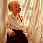 Mihya a rejoint le concours — aidez-le/la à gagner de superbes lots ! child, toddler, smile, curtains, white_blouse, black_skirt, earring, portrait, indoor, sunlight, shadow, hair, hand, standing, happy, warm_tone, soft_light, textile, collar, fashionable