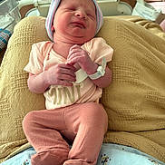 Rey is registered to the contest to win money with this photo: baby, newborn, infant, child, pink_clothing, striped_hat, blanket, hospital_bracelet, cute, sleepy, indoors, bed, soft_fabric, resting, portrait, small_hands, pink_pants, yellow_blanket, person, newborn_hat