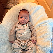 Logan is registered to the contest to win money with this photo: baby, infant, overalls, clothing, pattern, bird, cushion, blanket, cozy, indoor, floor, wood, carpet, foot, hand, face, person, cute, relaxing, portrait
