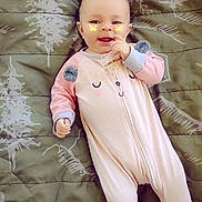 Wynter is registered to the contest to win money with this photo: baby, child, infant, smiling, lying_down, pink_outfit, onesie, blanket, bed, indoor, portrait, face, hands, baby_clothing, butterfly_stickers, patterned_background, cozy, happy, photography, cute