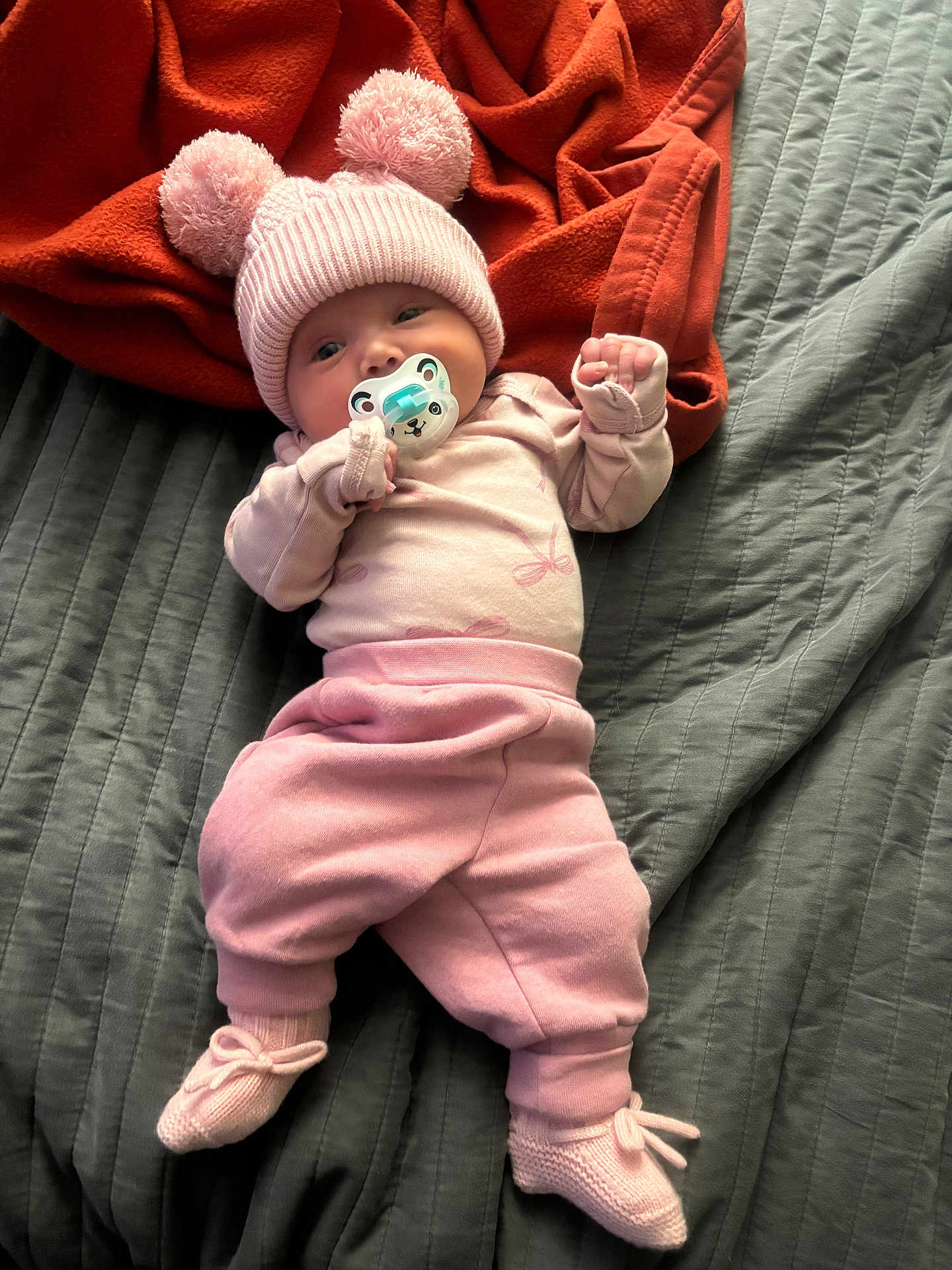 Everlynn joined the competition — help win amazing prizes! baby, pink_clothing, knit_hat, pom_poms, pacifier, blanket, orange_blanket, gray_blanket, infant, lying_down, cozy, soft_toys, knit_booties, cute, child, sleepwear, indoors, portrait, newborn, resting