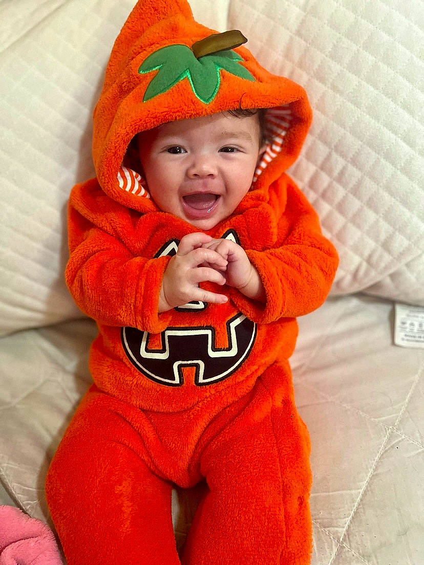 Mylah is registered to the contest to win money with this photo: baby, baby_toddler_clothing, cap, carmine, child, eye, fictional_character, happy, hat, head, headwear, hood, hoodie, human_body, jacket, orange, person, personal_protective_equipment, sleeve, smile