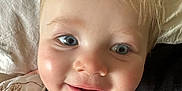 Teddy is registered to the contest to win money with this photo: toddler, child, smiling, face, blue_eyes, blonde_hair, close_up, pillow, soft_lighting, rosy_cheeks, casual_clothing, indoor, portrait, happy, baby, young_child, cute, skin, expression, head