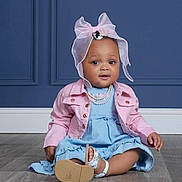 Jukenthya is registered to the contest to win money with this photo: baby, child, girl, sitting, floor, blue_dress, pink_jacket, headwear, bow, pearl_necklace, sandal, wood_floor, indoor, portrait, cute, smiling, fashion, accessory, curious, studio
