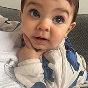 Isaac joined the competition — help win amazing prizes! baby, child, face, hand, blanket, couch, clothing, portrait, indoors, curious, expression, cozy, young, infant, sitting, blue, white, soft, cute, person