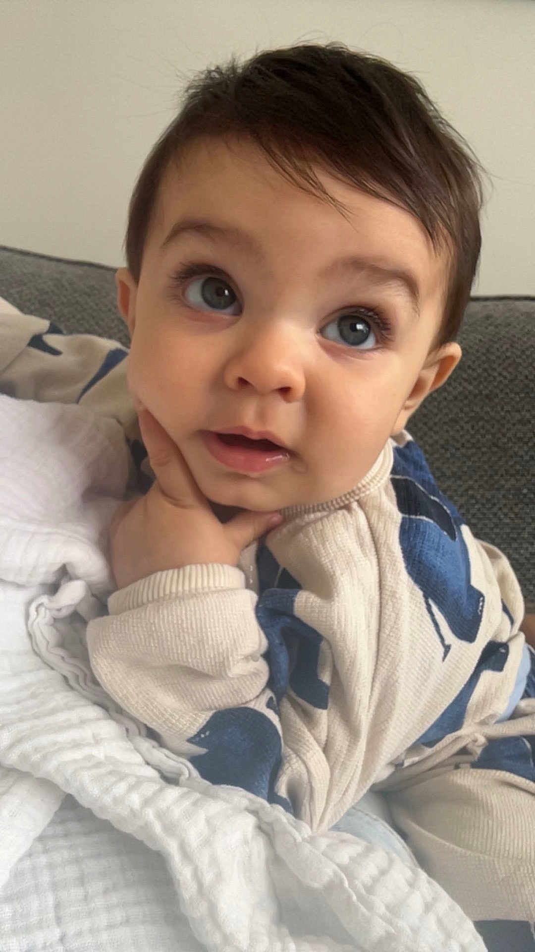 Isaac joined the competition — help win amazing prizes! baby, child, face, hand, blanket, couch, clothing, portrait, indoors, curious, expression, cozy, young, infant, sitting, blue, white, soft, cute, person
