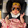 baby, infant, child, car_seat, sunglasses, yellow_headband, bow, pink_blanket, bow_pattern, blanket, harness, seat_padding, stroller, portrait, hand, face, reflection, clothing, cute, comfort