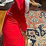 dog, red_hoodie, pet_clothing, indoor, carpet, wood_floor, pet_bed, looking_back, mischievous, cozy, furry, animal, holiday, christmas, hood, white_trim, cute, sitting, playful, domestic