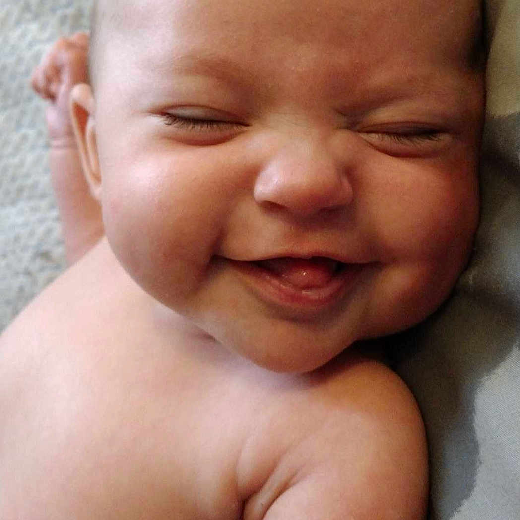 Oakleigh is registered to the contest to win money with this photo: arm, baby, cheeks, child, closeup, cute, expression, face, happy, head, human, infant, lying_down, newborn, portrait, skin, sleepy, smiling, soft, tongue