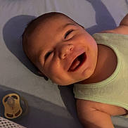 Liam participe au concours pour gagner de l'argent avec cette photo : baby, smiling, infant, lying_down, pacifier, plush_toy, elephant_toy, crib, soft_surface, tank_top, happy, cute, indoors, shadow, child, face, expression, skin, clothing, nursery