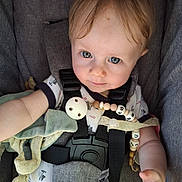 Jules a rejoint le concours — aidez-le/la à gagner de superbes lots ! baby, blue_eyes, car_seat, child, closeup, clothing, comfort, cute, expression, face, hair, hand, indoor, infant, onesie, pacifier_clip, seatbelt, skin, straps, young
