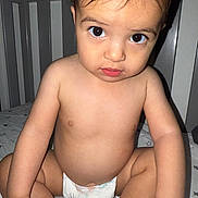Araceli is registered to the contest to win money with this photo: baby, baby_bed, bed, big_eyes, child, closeup, crib, cute, diaper, expression, furniture, indoors, infant, looking_at_camera, person, portrait, sitting, skin, toddler, young_child