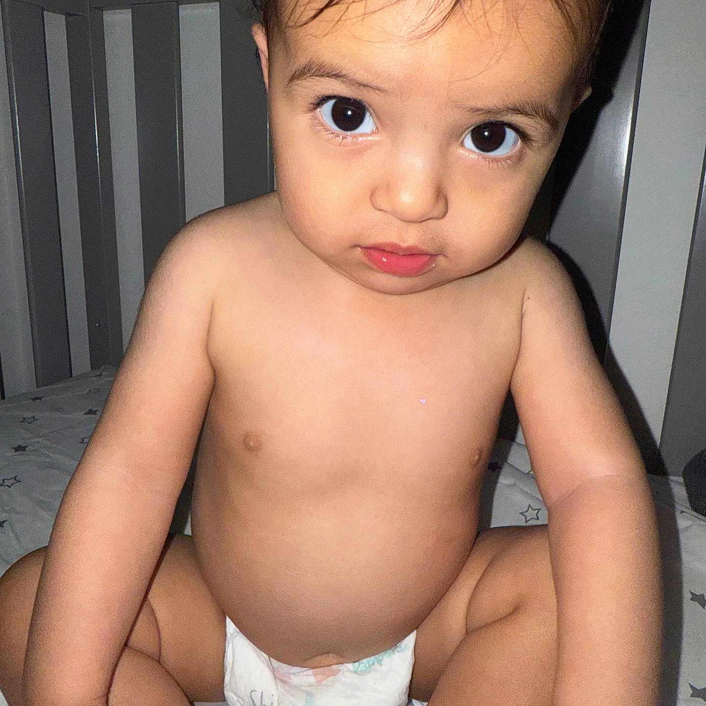 Araceli is registered to the contest to win money with this photo: baby, baby_bed, bed, big_eyes, child, closeup, crib, cute, diaper, expression, furniture, indoors, infant, looking_at_camera, person, portrait, sitting, skin, toddler, young_child