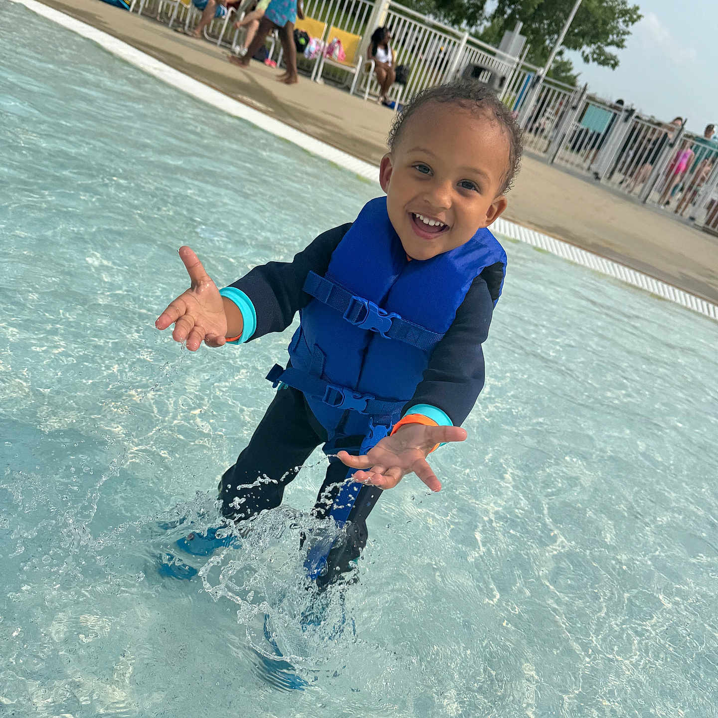 Izlan is registered to the contest to win money with this photo: child, daytime, fence, happy, leisure, life_jacket, outdoor, people, play, pool, recreation, smiling, splashing, summer, sunny, swimwear, toddler, trees, water, water_splash