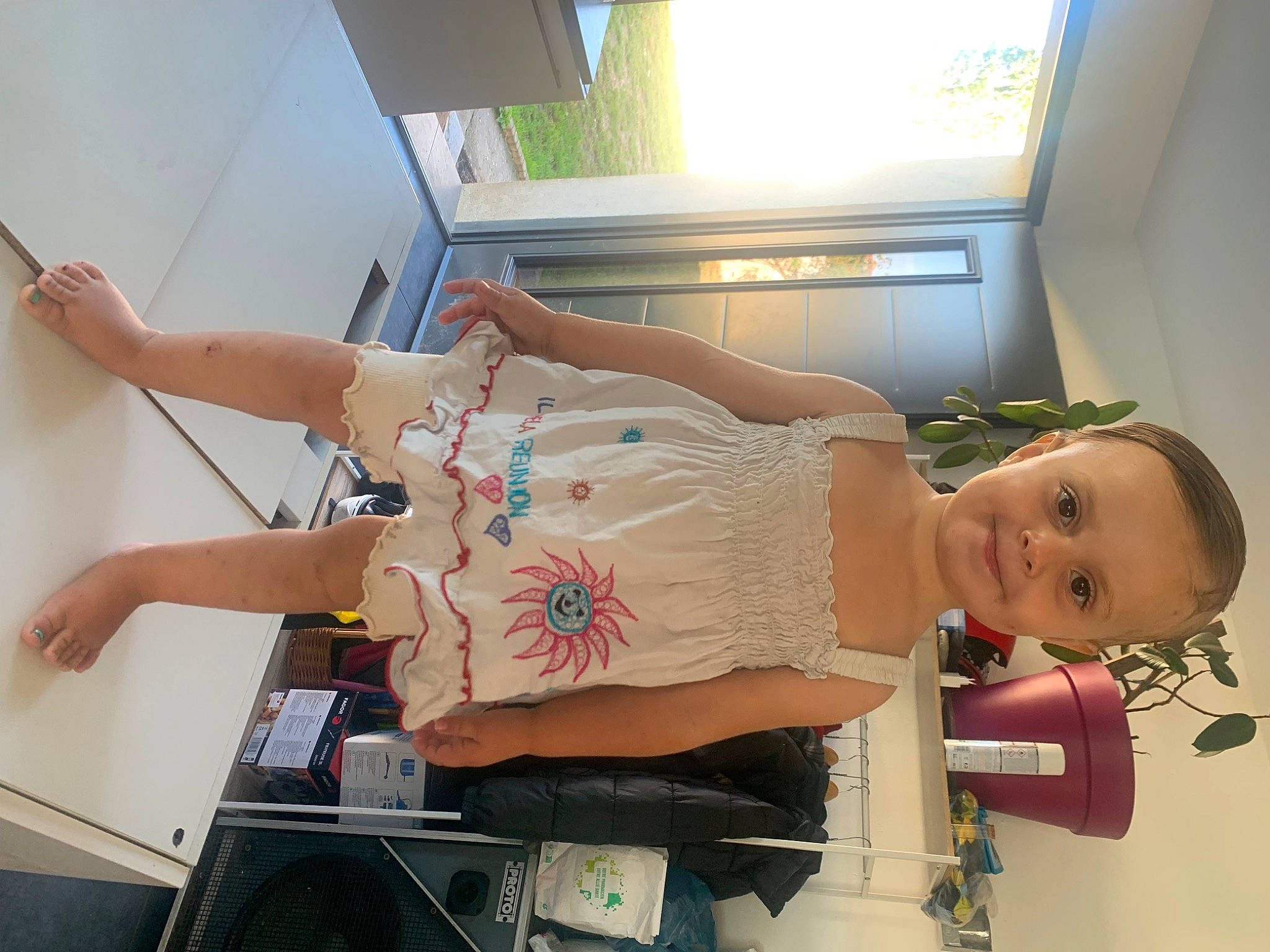 Helena participe au concours pour gagner de l'argent avec cette photo : abdomen, baby, chest, elbow, fun, gesture, happy, human_leg, knee, machine, plant, room, shoulder, smile, thigh, toddler, trunk, waist, window, wrist