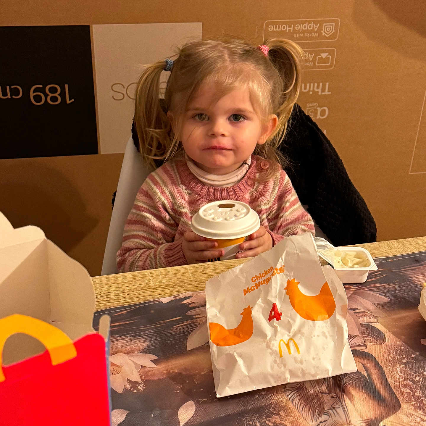 Aria a rejoint le concours — aidez-le/la à gagner de superbes lots ! child, girl, pigtails, blonde_hair, sweater, table, cup, fast_food, mcdonalds, food_packaging, happy, indoor, dining, meal, person, portrait, smile, cute, snack, cozy