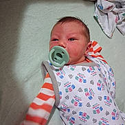 Michael joined the competition — help win amazing prizes! newborn, baby, infant, child, portrait, pacifier, onesie, sleepwear, bed, changing_pad, blanket, textile, lying_down, face, eyes, hair, red_hair, colorful_clothing, nursery, indoors