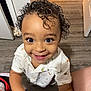 toddler, child, smiling, curly_hair, shirt, indoor, wooden_floor, happy, person, looking_up, eyes, face, legs, socks, shoes, doorway, home, cute, portrait, young_child