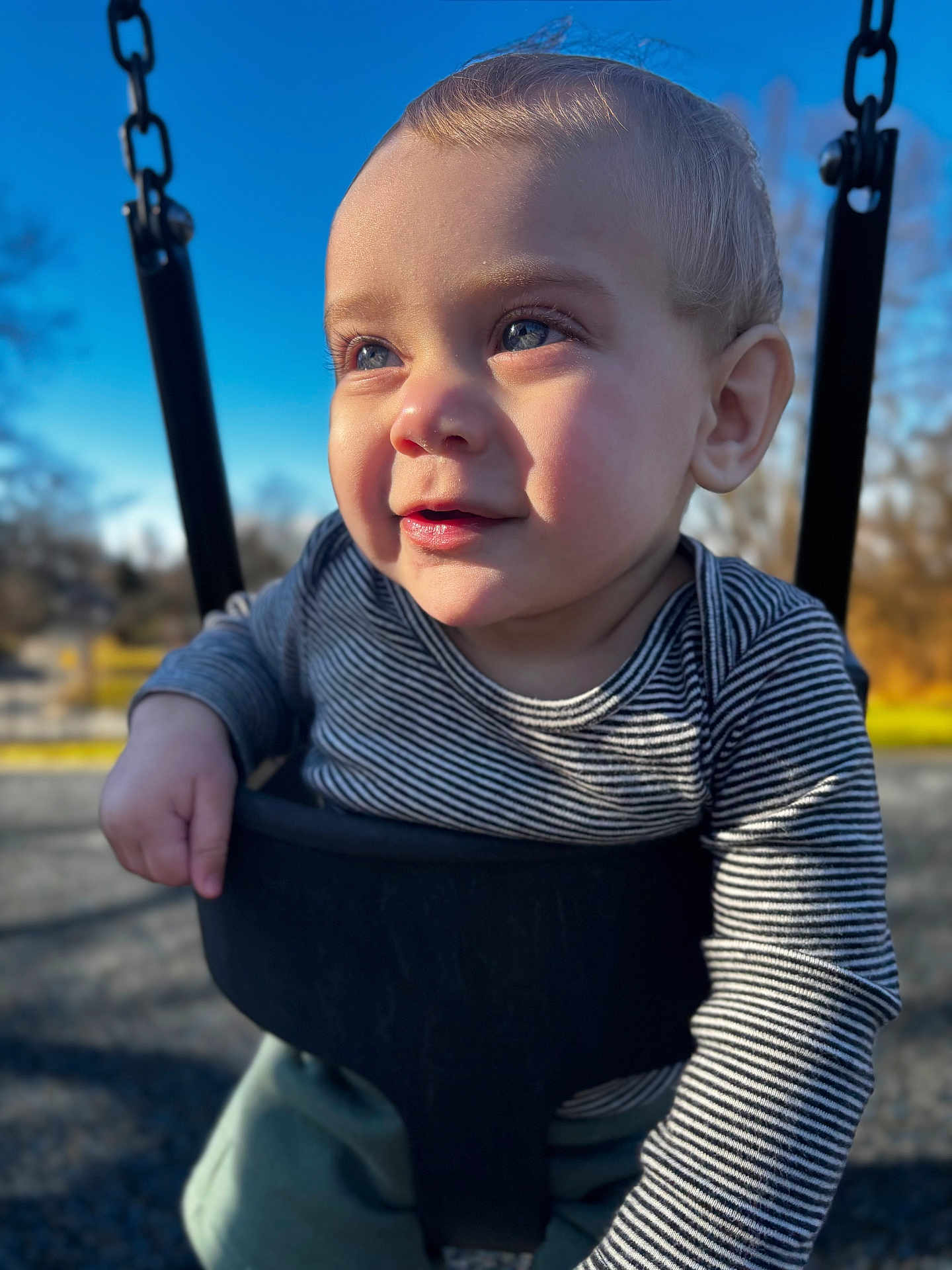 Sage joined the competition — help win amazing prizes! child, baby, toddler, swing, playground, outdoor, blue_sky, sunlight, portrait, closeup, striped_shirt, green_pants, smile, eyes, chubby_cheeks, chain, seat, bokeh, shadow, happy