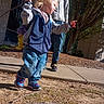 Anubis is registered to the contest to win money with this photo: child, toddler, person, jeans, jacket, sneakers, side_view, outdoor, daylight, stick, tree, sidewalk, building, adult, shadow, nature, playful, walking, casual_clothing, backpack