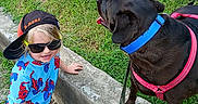 Anubis joined the competition — help win amazing prizes! child, toddler, dog, black_dog, sunglasses, cap, sideways_cap, blue_shirt, spiderman_pattern, leash, grass, concrete, sidewalk, walking, pet, outdoor, sunny, happy, casual_clothing, footwear