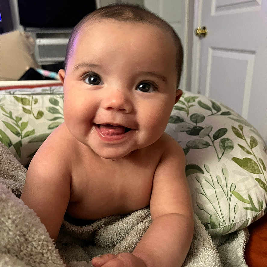 Adrianna is registered to the contest to win money with this photo: baby, blanket, child, couch, cute, expression, eyes, face, happy, head, indoor, infant, person, pillow, portrait, room, skin, smiling, towel, young