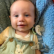 Oliver joined the competition — help win amazing prizes! baby, smiling, infant, overalls, bunny, pacifier, blanket, blue, clothing, cute, happy, face, child, lying_down, soft, comfort, indoors, closeup, button, person