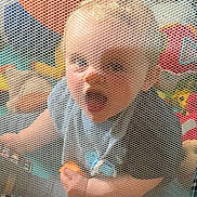Tye is registered to the contest to win money with this photo: baby, child, playpen, mesh, toy, indoor, curious, expression, clothing, floor, checkered, pattern, colorful, soft, person, infant, cute, hand, face, mouth
