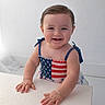 baby, blue_eyes, bracelet, brown_hair, child, cute, dress, hands, happy, home, indoor, patriotic, photography, portrait, red_white_blue, seated, smiling, soft_lighting, table, wall