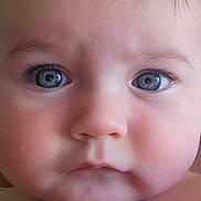 Jazmine is registered to the contest to win money with this photo: apparel, baby, blue_eyes, child, chubby_cheeks, closeup, curly_hair, cute, expression, eyelashes, face, hair, indoors, infant, natural_light, person, portrait, purple, skin, young
