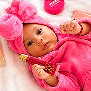 Amira joined the competition — help win amazing prizes! baby, pink_robe, bow, cosmetics, lip_gloss, soft_surface, face, hand, cute, infant, child, beauty_products, lying_down, portrait, wide_eyes, skin_care, adorable, colorful, indoors, product