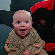 Iris joined the competition — help win amazing prizes! baby, smiling, blue_eyes, knitted_sweater, hands, adult, couch, indoor, person, happy, seated, holding, face, head, clothing, furniture, cozy, portrait, infant, child