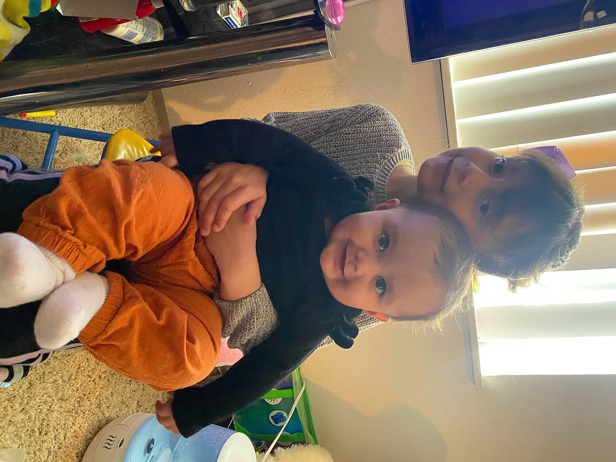 Harper is registered to the contest to win money with this photo: abdomen, baby, bag, child, comfort, eyewear, fun, happy, hat, human_leg, joy, lap, luggage_and_bags, mouth, person, room, sitting, smile, t_shirt, thigh